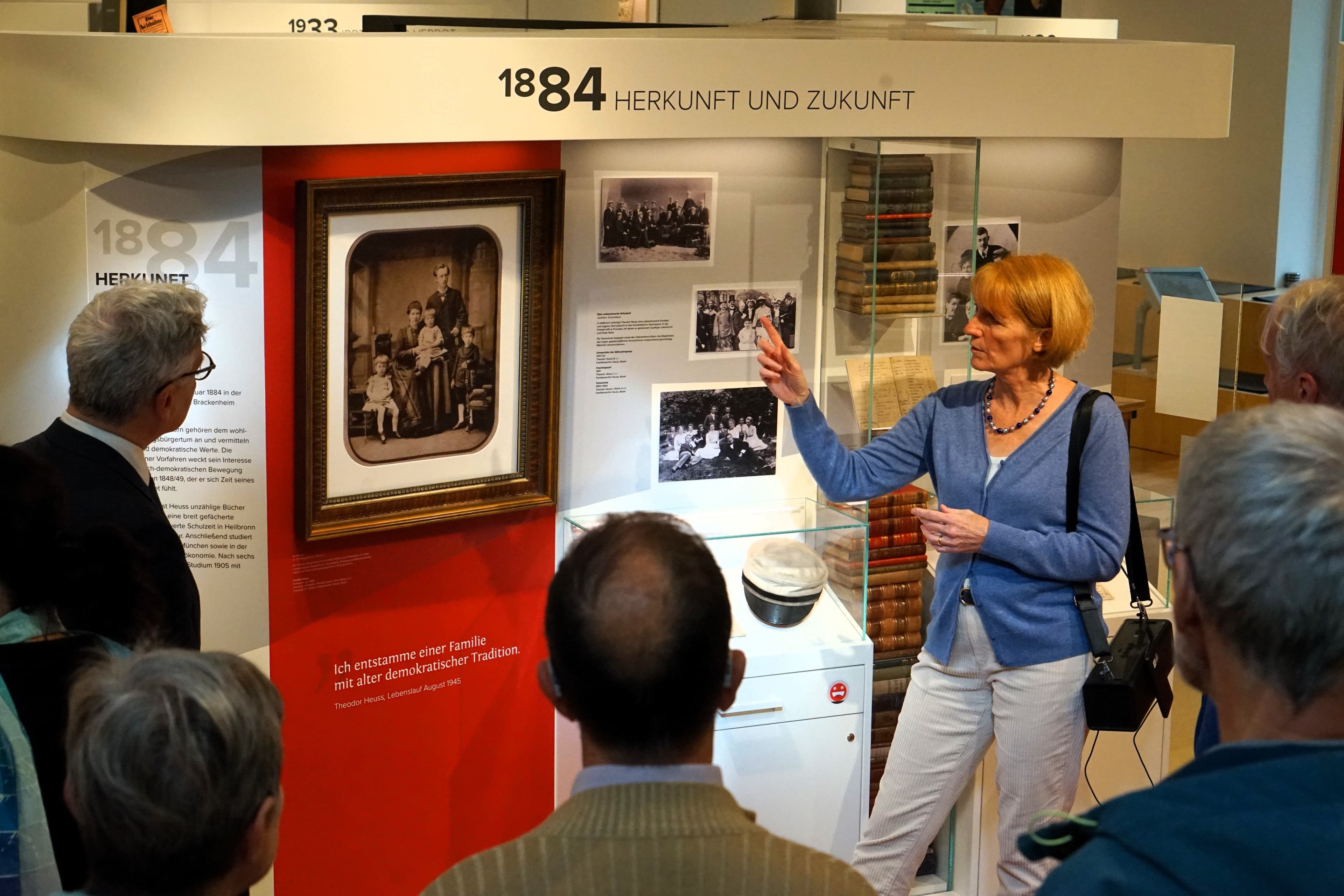 Eine Führung im Theodor-Heuss-Haus. Eine Gruppe steht vor dem Familienfoto der Familie Heuss.